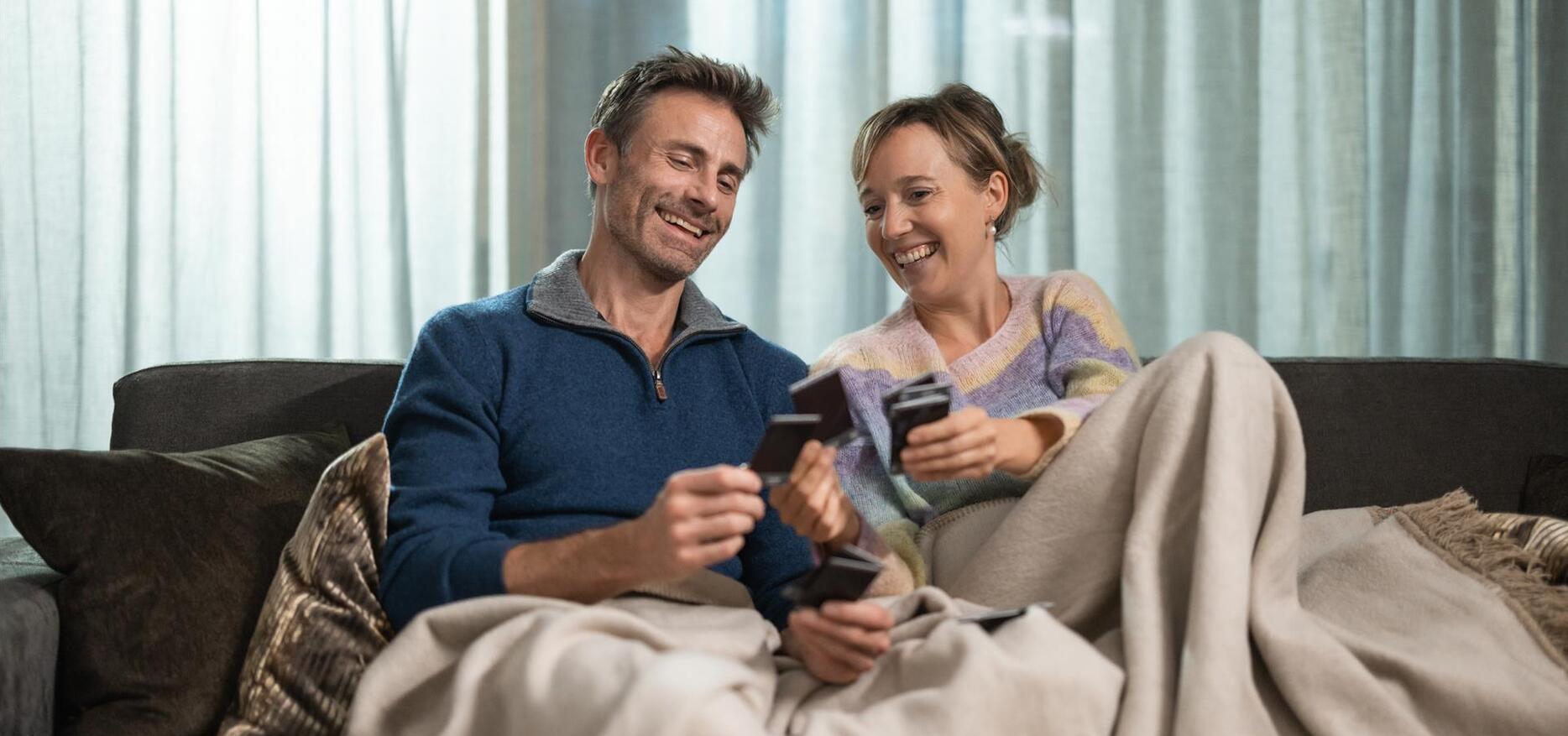 A man and a woman are lying on a lounger and playing cards