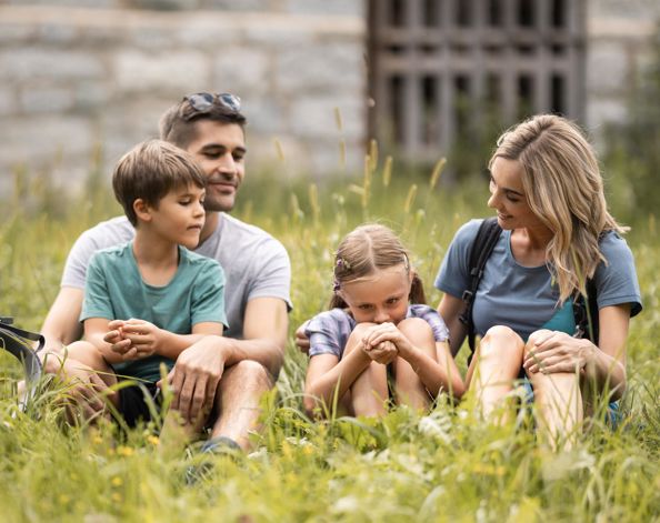 A family is sitting in a meadow