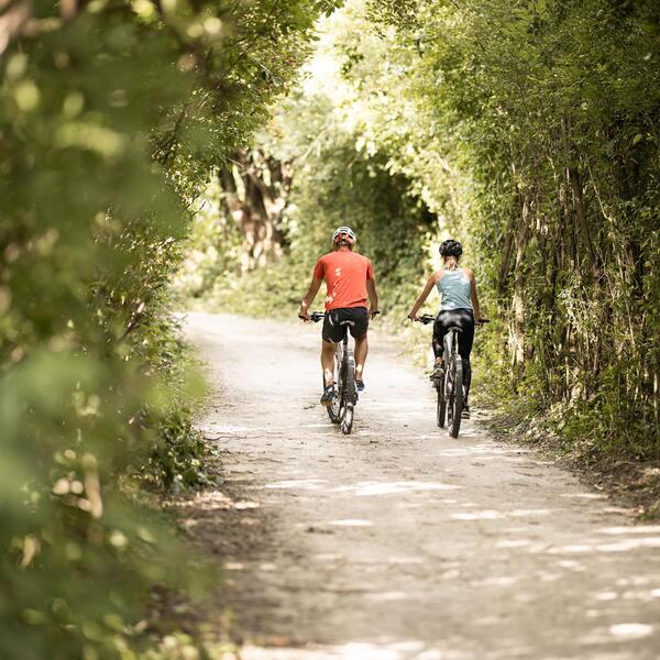 A man and a woman are riding a bike