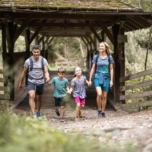 A family is hiking across the bridge in the Rienz Gorge