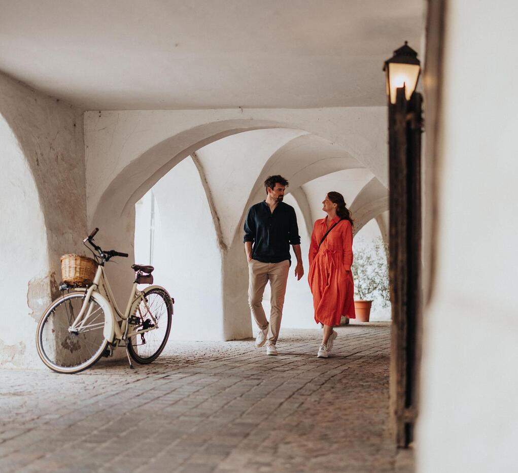 A man and a woman are walking through an alley.