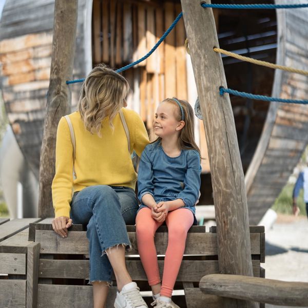 Eine Frau spielt mit einem Kind auf dem Spielplatz Apfelgarten