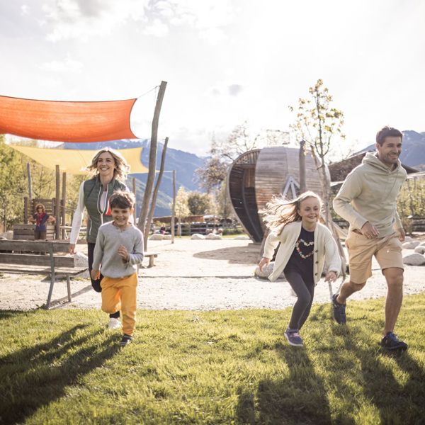 Eine Familie mit zwei Kindern spielen auf dem Spielplatz Apfelgarten