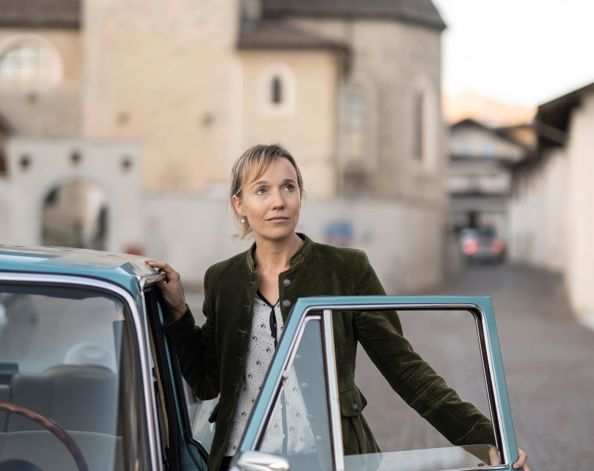 Eine Frau steht an der Tür eines Oldtimers