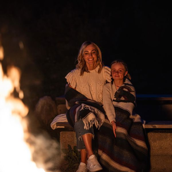 Eine Frau und ein Kind sitzen vor einem Lagerfeuer