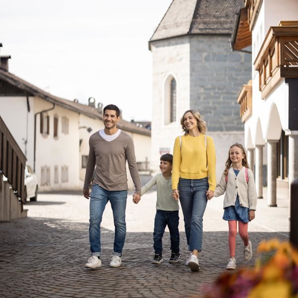Eine Familie mit zwei Kindern spaziert durch Natz