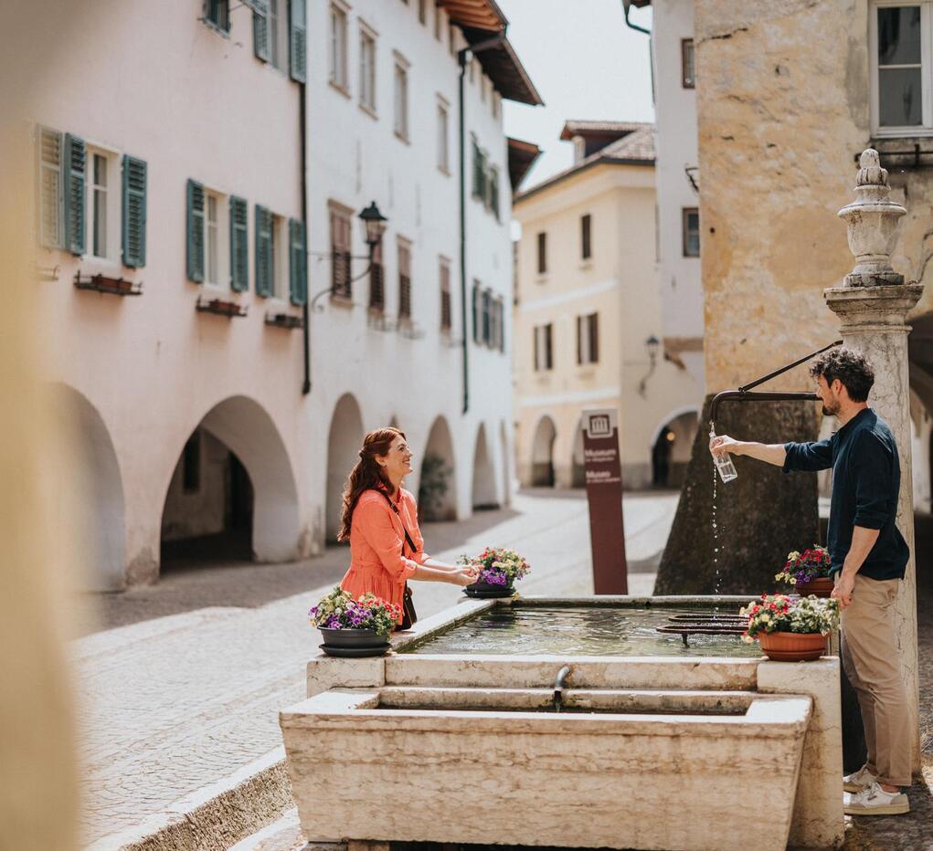 A woman and a man standing by a fountain.