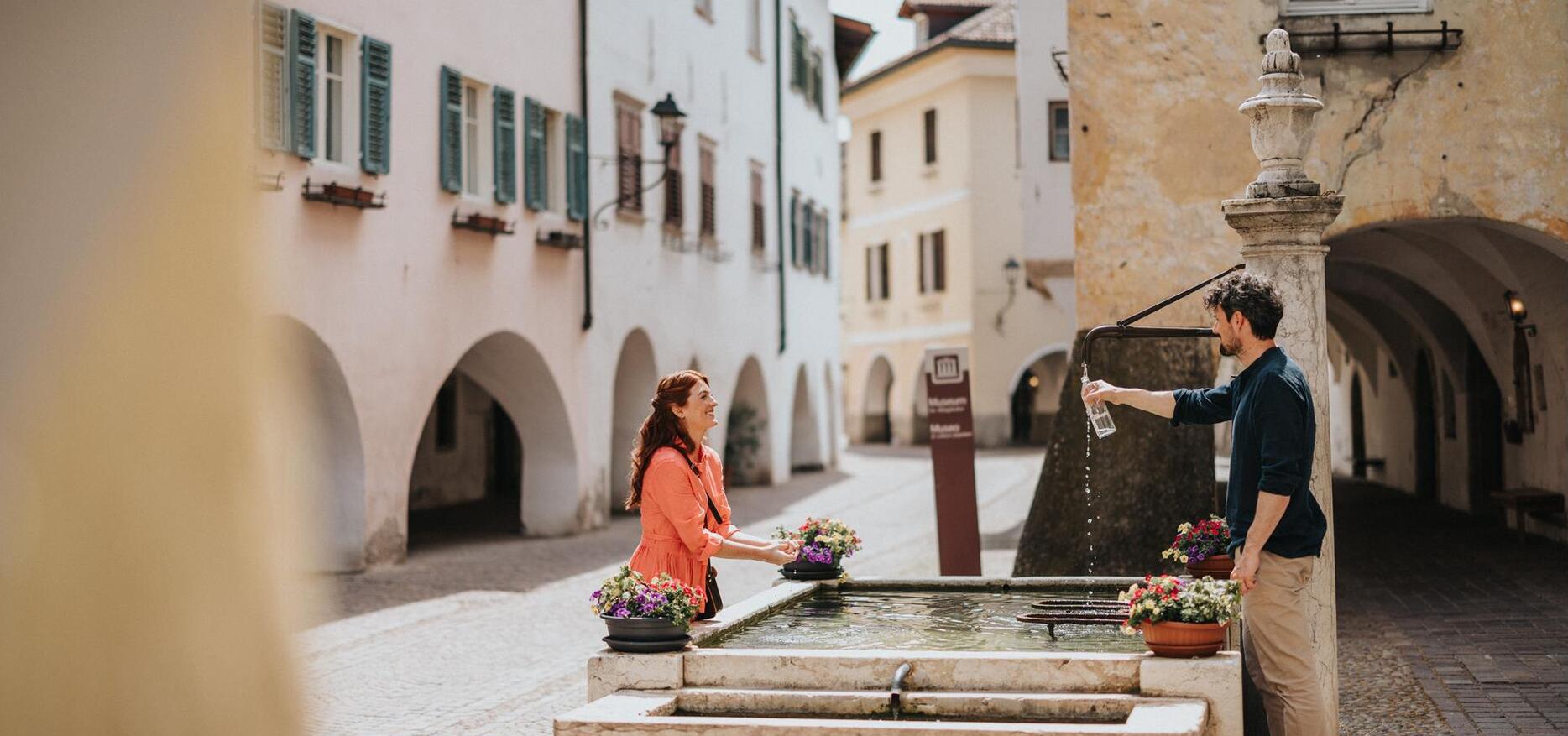 A woman and a man standing by a fountain.