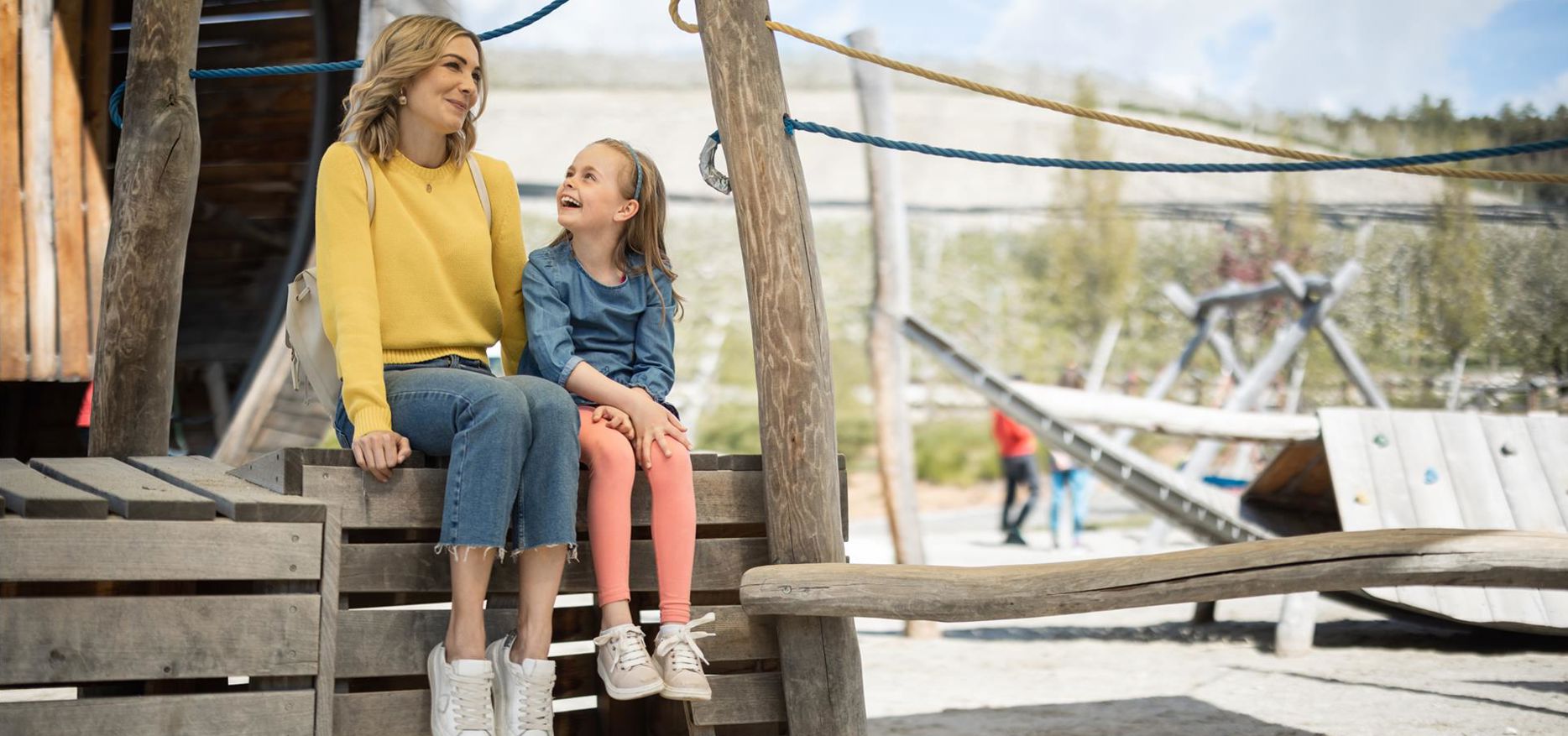 Eine Frau spielt mit einem Kind auf dem Spielplatz Apfelgarten