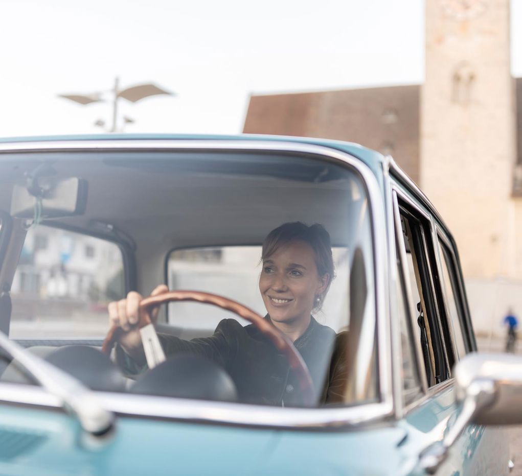 Una donna è seduta in un’auto d’epoca.