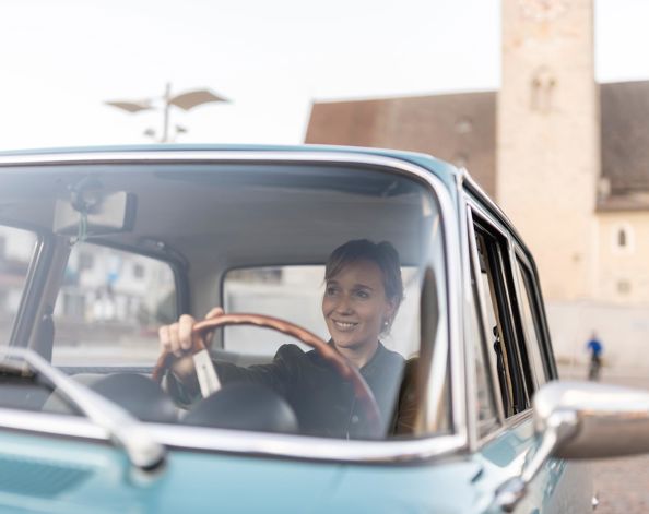 Una donna è seduta in un’auto d’epoca.