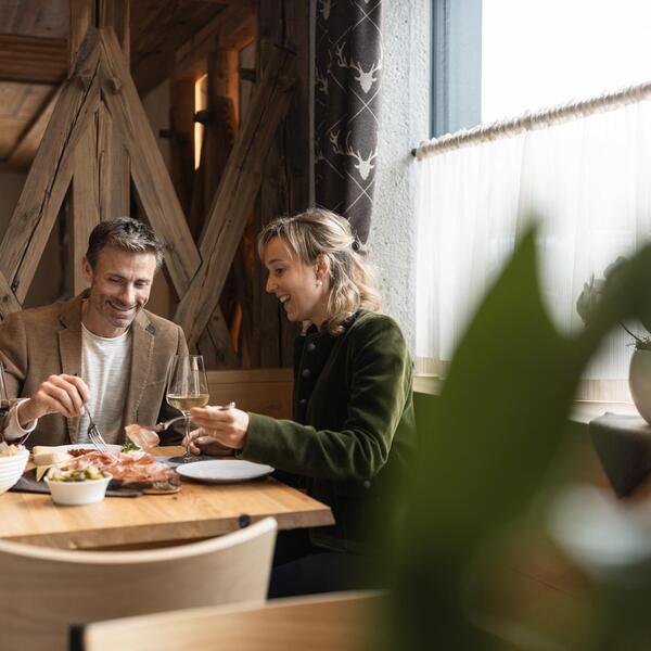 Ein Mann und eine Frau sitzen an einem Tisch und essen typische Südtiroler Gerichte