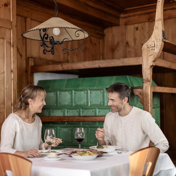 Ein Mann und eine Frau sitzen in einer gemütlichen Stube und genießen gemeinsam Schlutzkrapfen und Knödel